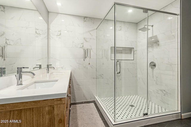 bathroom with a shower with door, tile walls, and vanity