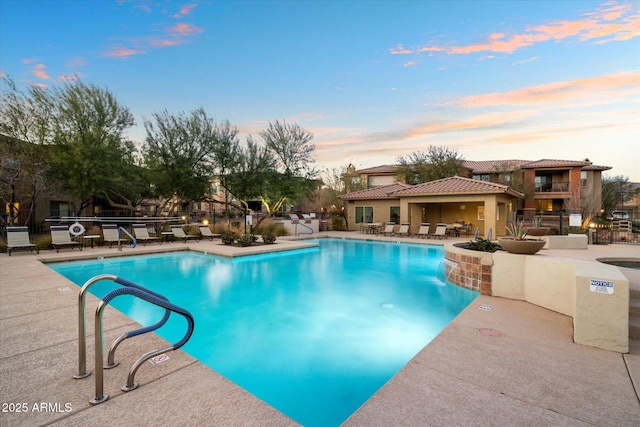 pool at dusk featuring a patio area