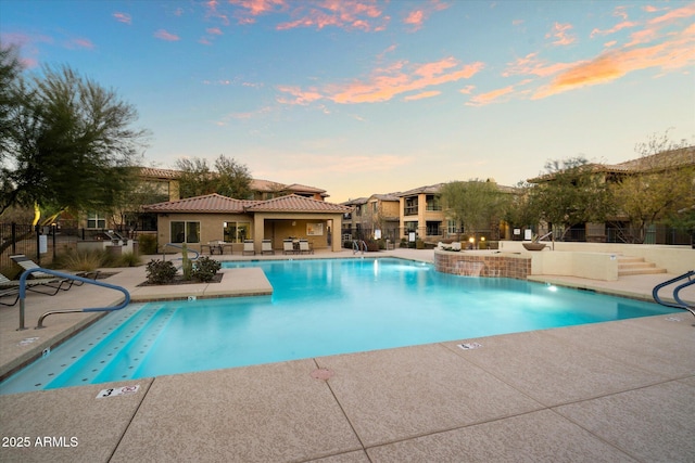 pool at dusk featuring a patio area