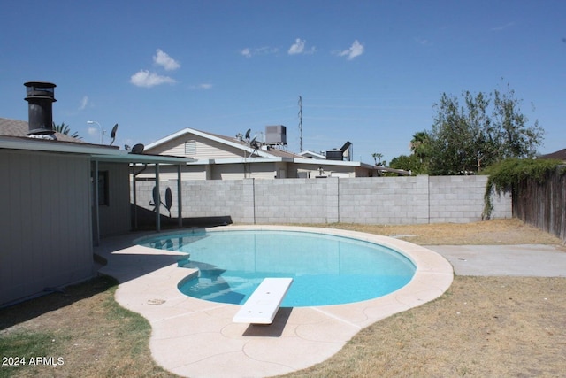 view of swimming pool with a diving board and a patio