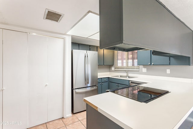 kitchen featuring sink, light tile patterned floors, stainless steel fridge, and kitchen peninsula