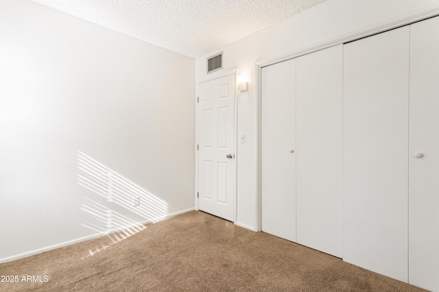 unfurnished bedroom featuring carpet floors, a closet, and a textured ceiling