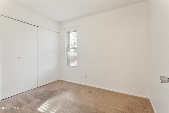 unfurnished bedroom with light colored carpet, a closet, and a textured ceiling