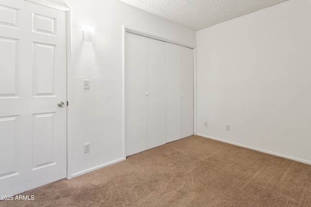 unfurnished bedroom with carpet floors, a closet, and a textured ceiling