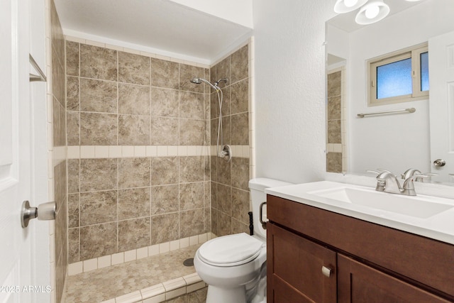 bathroom featuring tiled shower, vanity, and toilet