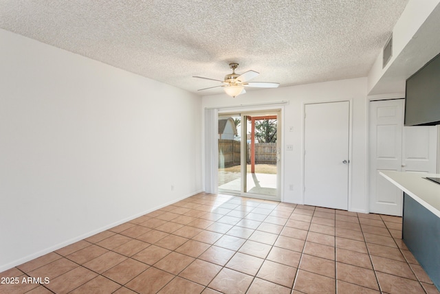 interior space with ceiling fan, a textured ceiling, and light tile patterned floors