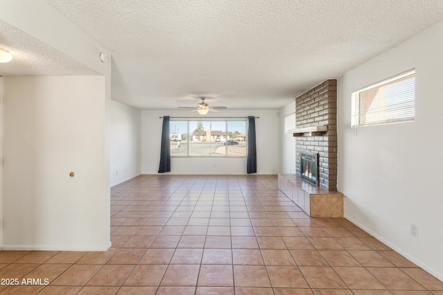 unfurnished living room with a brick fireplace, plenty of natural light, light tile patterned floors, and ceiling fan