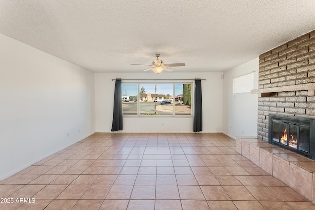 unfurnished living room featuring a brick fireplace, a textured ceiling, ceiling fan, and light tile patterned flooring