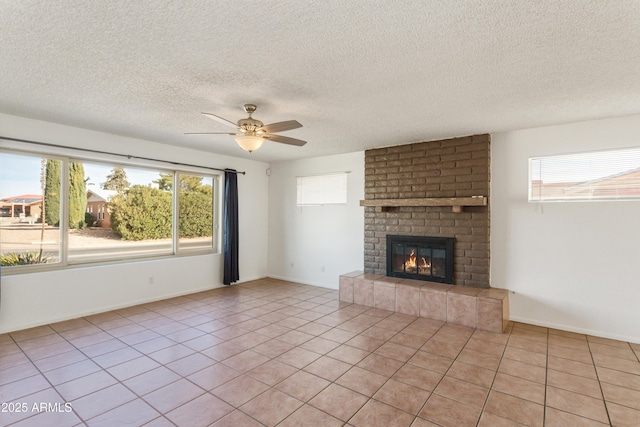 unfurnished living room featuring a brick fireplace, light tile patterned floors, a wealth of natural light, and ceiling fan