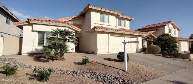 mediterranean / spanish home featuring concrete driveway, an attached garage, a tile roof, and stucco siding