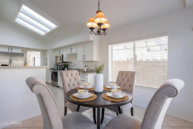 dining space with light tile patterned floors, a chandelier, baseboards, and vaulted ceiling