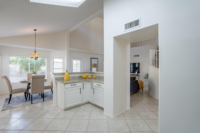 kitchen with light tile patterned floors, visible vents, a peninsula, pendant lighting, and a notable chandelier