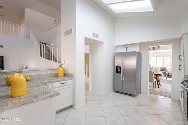 kitchen with visible vents, high vaulted ceiling, light tile patterned flooring, and stainless steel fridge with ice dispenser