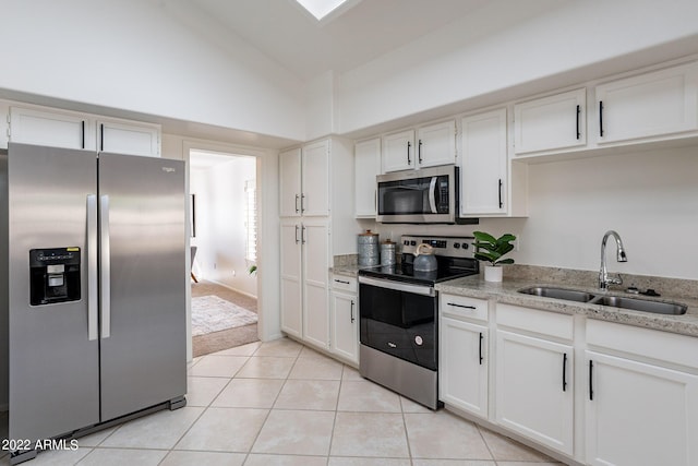 kitchen with a sink, appliances with stainless steel finishes, white cabinets, light tile patterned floors, and light stone countertops