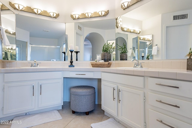 bathroom featuring a sink, visible vents, double vanity, and tile patterned flooring