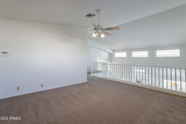 carpeted empty room featuring visible vents, a ceiling fan, lofted ceiling, and baseboards