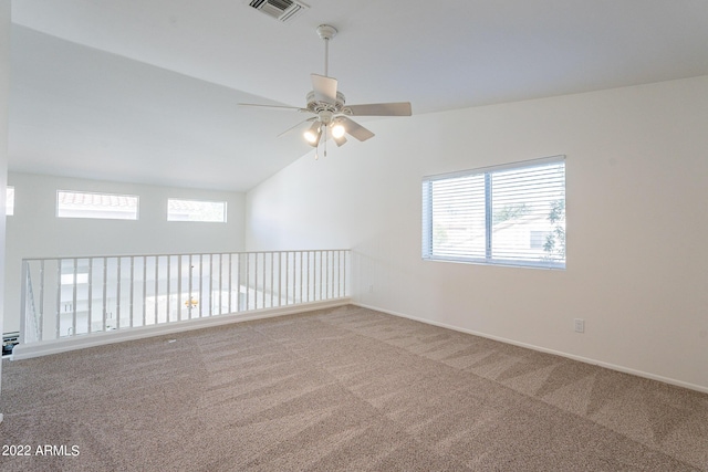 empty room featuring lofted ceiling, carpet flooring, a ceiling fan, and visible vents