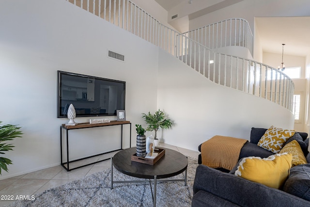 living area with visible vents, baseboards, a chandelier, a high ceiling, and tile patterned floors