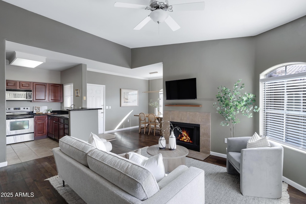 living room with a fireplace, wood finished floors, a ceiling fan, and baseboards