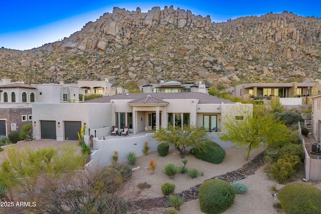 view of front facade with a garage, driveway, a mountain view, and stucco siding