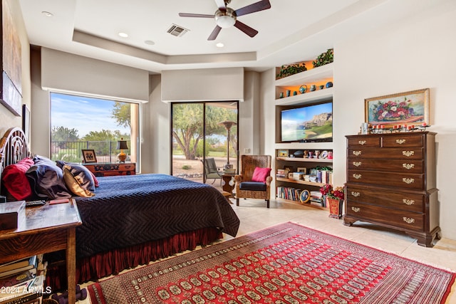 bedroom featuring access to exterior, light tile patterned floors, a tray ceiling, and ceiling fan