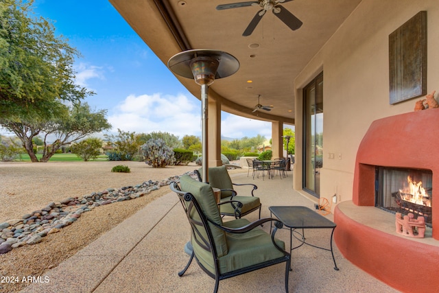 view of patio / terrace featuring ceiling fan and an outdoor fireplace