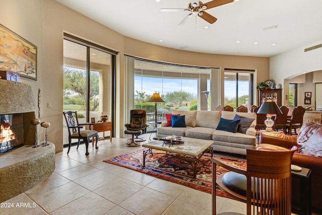 living room featuring a premium fireplace, light tile patterned floors, and ceiling fan