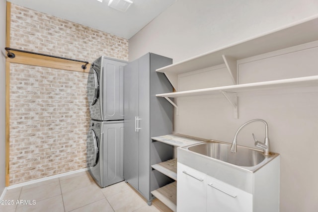10160 E Harvest Rd, Florence, AZ 85132 - laundry area with stacked washer / dryer, light tile patterned floors, baseboards, brick wall, and cabinet space