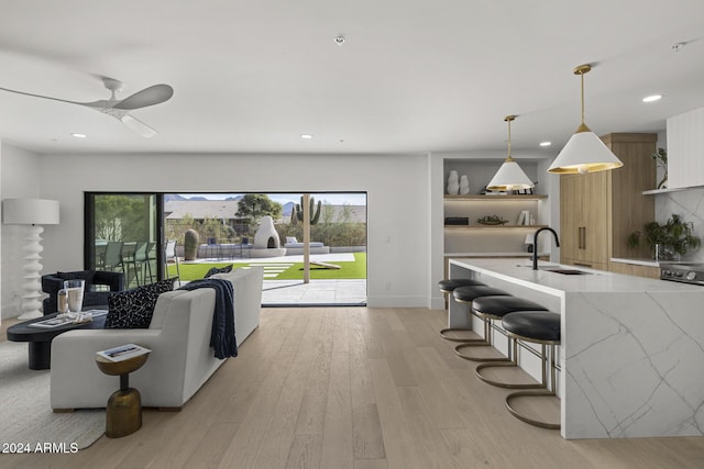 living room featuring ceiling fan, light hardwood / wood-style floors, and sink