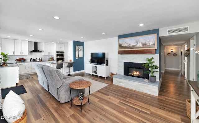 living area with recessed lighting, visible vents, a fireplace, and wood finished floors