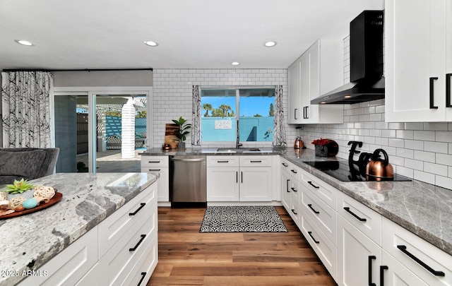 kitchen featuring wood finished floors, white cabinets, wall chimney range hood, backsplash, and dishwasher