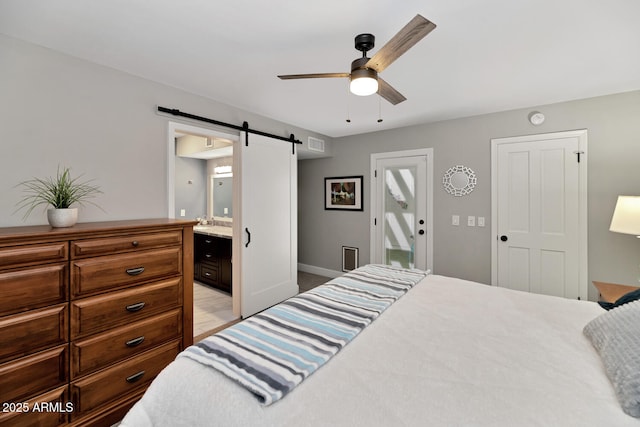 bedroom featuring a barn door, visible vents, a ceiling fan, connected bathroom, and a sink