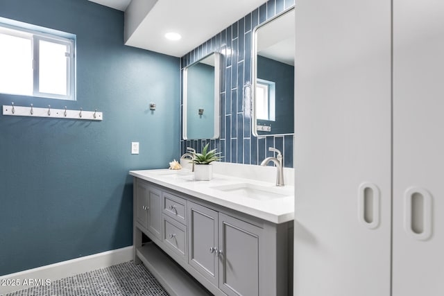 bathroom featuring double vanity, a sink, baseboards, and tile patterned floors