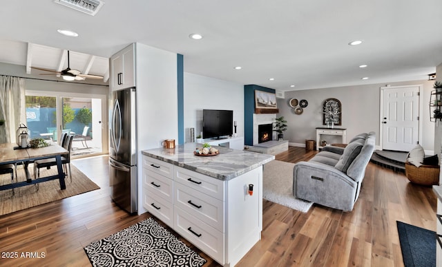 living area with visible vents, a ceiling fan, wood finished floors, a fireplace, and recessed lighting