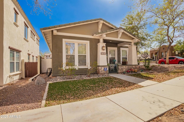 view of front of property with a porch, a tile roof, fence, and stucco siding