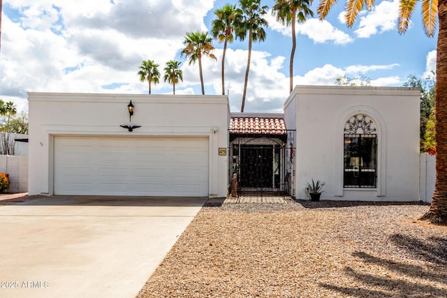 view of front of home featuring a gate, fence, an attached garage, stucco siding, and concrete driveway