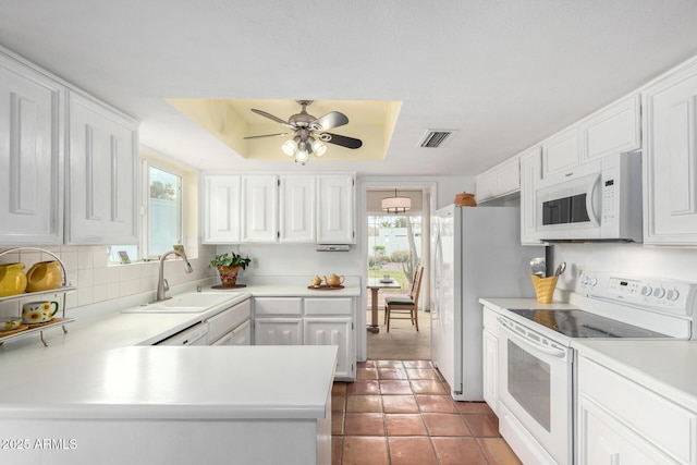 kitchen with white appliances, visible vents, a sink, white cabinetry, and a raised ceiling