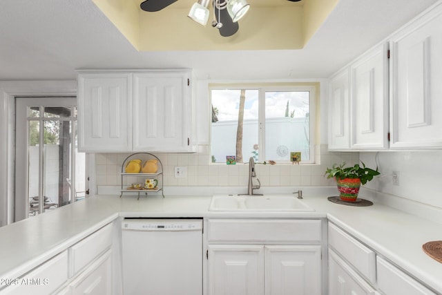 kitchen with light countertops, decorative backsplash, white dishwasher, white cabinets, and a sink