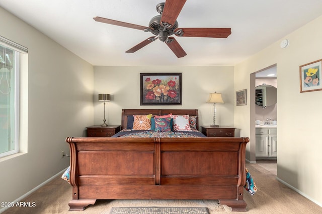 carpeted bedroom with a ceiling fan, baseboards, ensuite bathroom, and a sink