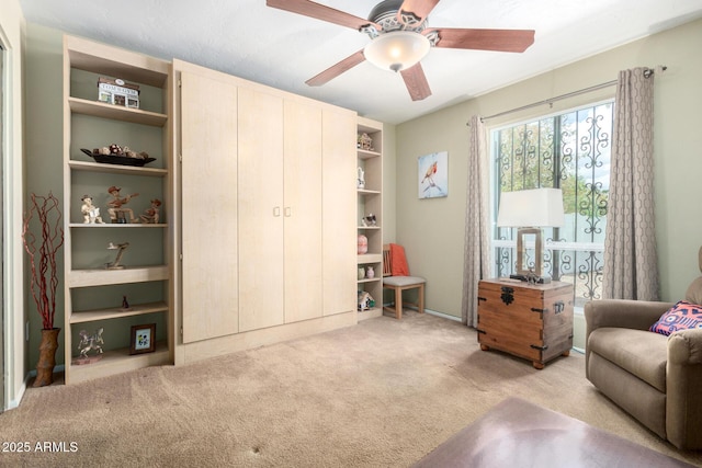 living area featuring light colored carpet and a ceiling fan