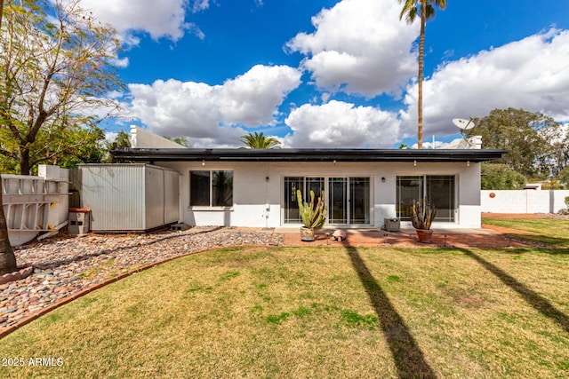 rear view of house featuring a patio, fence, a lawn, and stucco siding