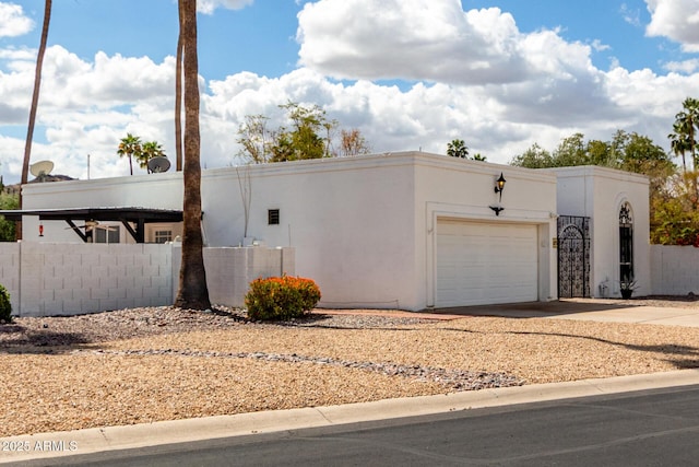 view of front of property featuring fence, a garage, driveway, and stucco siding