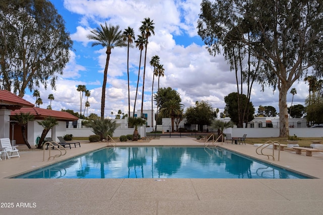 community pool with a patio and fence