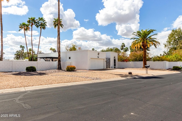 view of front of house with a fenced front yard, stucco siding, an attached garage, and concrete driveway