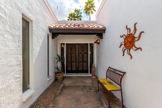 property entrance with stucco siding and a tile roof