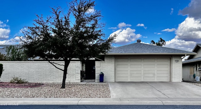 ranch-style home featuring a garage, concrete driveway, brick siding, and roof with shingles