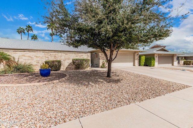 single story home with a shingled roof, concrete driveway, brick siding, and an attached garage