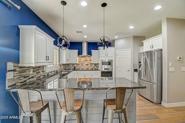 10249 E Kinetic Dr, Mesa, AZ 85212 - kitchen featuring stainless steel appliances, wall chimney exhaust hood, a peninsula, light wood-style floors, and tasteful backsplash