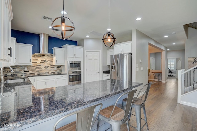 10249 E Kinetic Dr, Mesa, AZ 85212 - kitchen featuring appliances with stainless steel finishes, wall chimney exhaust hood, a sink, backsplash, and a peninsula