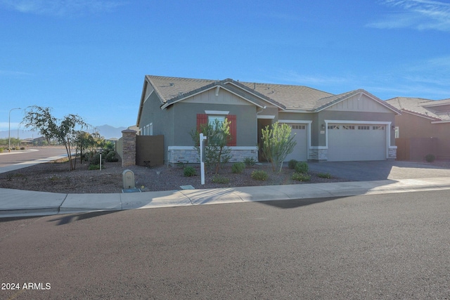 view of front of home with an attached garage, driveway, stucco siding, and stone siding